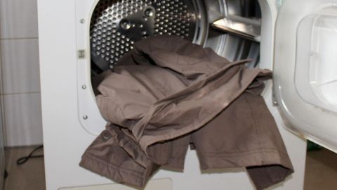 Ein Anorak liegt in einem Wäschetrockner, der offen ist, und zeigt, dass keine Tennisbälle vorhanden sind.