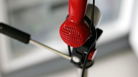 Ein roter Haartrockner auf einem Stativ bläst warme Luft aus, um das Gefrierfach abzutauen, während es in einer Küche steht.