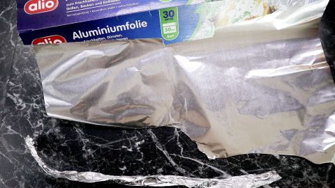 Einfach mal Alustreifen anstelle von herkömmlichen Papilotten verwenden! Alu-Papilotten werden vorbereitet, während eine Rolle Aluminiumfolie auf einer dunklen Oberfläche sichtbar ist.