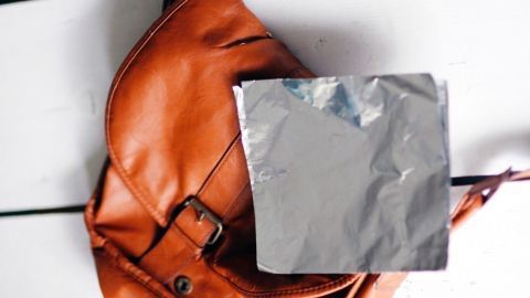 Ein brauner Tasche liegt auf einem Tisch, während ein silberner Wärmeschutz auf ihr platziert ist, um Wärme zu spenden.
