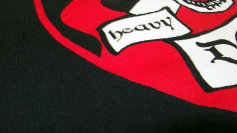Ein T-Shirt mit einem auffälligen, roten und schwarzen Aufdruck zeigt ein kreatives Design. Der Aufdruck ist teilweise beschädigt und benötigt eine Auffrischung.