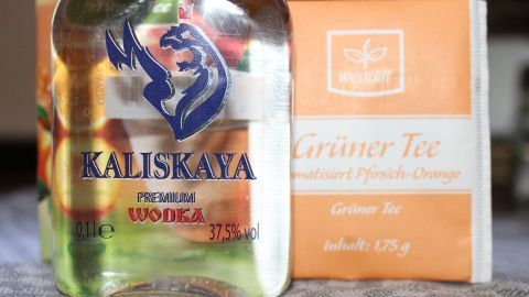 Wer Grünen Tee mag, wird es lieben. (Die Mischung kann ruhig härter sein, der Wodka kommt nicht sehr zum Vorschein.) Eine Flasche Kalisawa Wodka steht neben einer Packung grüner Tee auf einem Tisch, bereit für ein erfrischendes Getränk.