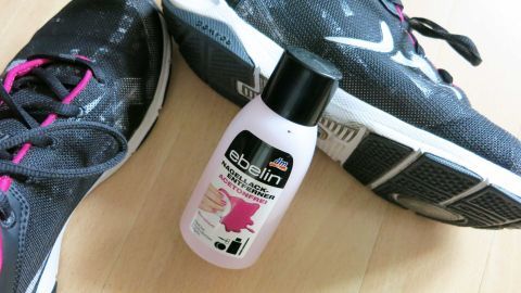 Ohne Probleme bekommt man schwarze Streifen an Schuhen mit Nagellackentferner entfernt. Die Farbe bleicht dabei nicht aus. Schwarze Sportschuhe liegen auf einem Boden neben einer Flasche Nagellackentferner, bereit zur Reinigung.