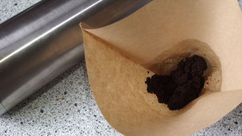 Eine silberne thermoskanne steht neben einem Kaffeefilter mit verschüttetem Kaffee, für geruchsneutrale Nutzung.
