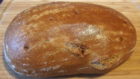 Ein frisch gebackenes Brot liegt auf einem Holzbrett, bereit für den Verkauf um 18.00 Uhr zu einem günstigeren Preis.