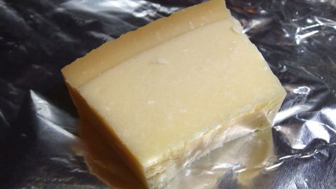 Ein Stück Parmesan-Käse liegt auf Alufolie und wartet darauf, für eine Mahlzeit verwendet zu werden.