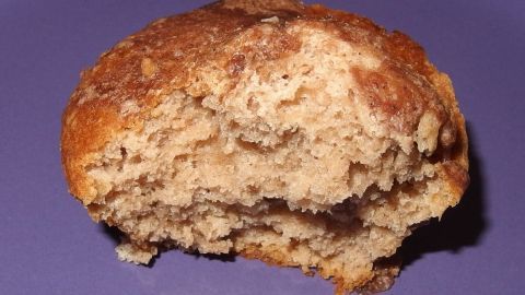 Ein fluffiges, saftiges Brötchen liegt auf einem Teller. Es zeigt eine goldbraune Oberfläche und eine lockere Krume.