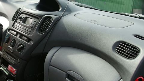 Das Armaturenbrett eines Autos zeigt eine saubere, glatte Oberfläche mit Bedienelementen, umgeben von einem modernen Innenraum.