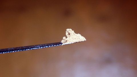 Bei Durchfall einfach eine Teelöffelspitze Zimt pur essen und mit einem Glas Wasser nachspülen. Ein kleiner Zimtstaub sitzt auf einem dünnen Löffel in der Nähe einer Holzoberfläche, bereit zur Verwendung gegen Durchfall.