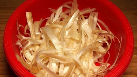Dünne Spargelschalen liegen in einer roten Schüssel und warten darauf, für die einfache Spargelsuppe verwendet zu werden.