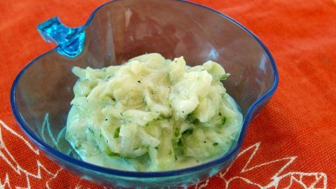 Ein Gurkensalat ohne Dill in einer blauen Schüssel auf einem roten Tischdecke präsentiert, frisch und ansprechend.