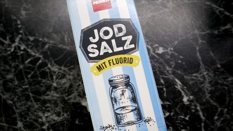 Eine Packung Jodsalz steht auf einer marmorartigen Oberfläche und wirkt als Heilmittel zur Linderung von Herpes.