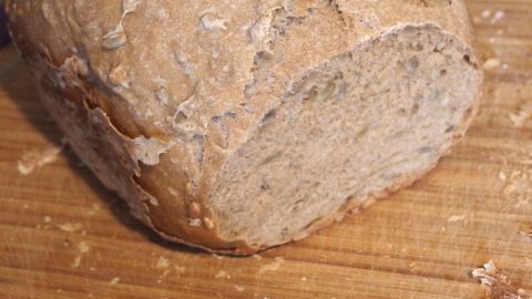 Ein frisches Brot liegt auf einem Holzbrett, gleichmäßig geschnitten und leicht krustig, bereit zum Servieren.