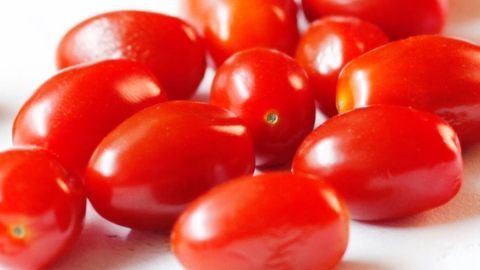 Saftige, rote Tomaten liegen auf einer weißen Fläche, bereit zur Zubereitung einer aromatischen Tomatensauce.