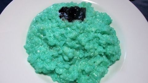 Ein Teller Milchreis in leuchtendem Blau mit einer dunklen Fruchtsoße obenauf, attraktiv für Kinder gestaltet.