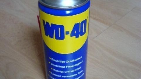 WD-40 Dose steht auf einem Holzfußboden. Text: "Beseitigt Quietschgeräusche, verdrängt Feuchtigkeit, reinigt und schützt, lockert verrostete Teile, lässt festsitzende Mechanik wieder laufen". Volumen: 400 ml.