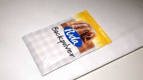Ein Päckchen Backpulver liegt auf einer weißen Oberfläche. Es ist für die Reinigung von weißer Wäsche gedacht.