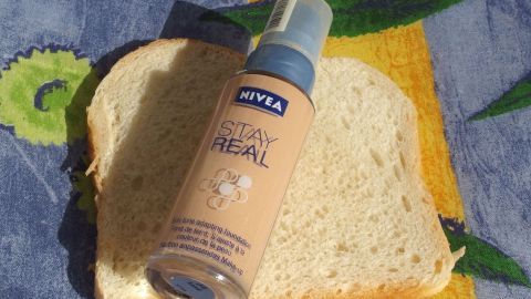 Ein Stück Toastbrot liegt neben einem Make-Up-Flakon, das zur Entfernung von Make-Up-Flecken an Kleidungsstücken genutzt wird.