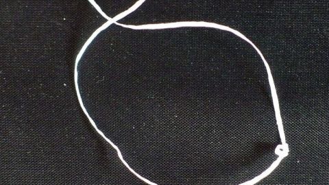 Größere Zahnzwischenräume mit Zahnseide sauber halten. Ein Zahnseidefaden liegt auf schwarzem Untergrund, bereit, die größeren Zahnzwischenräume zu reinigen und sauber zu halten.