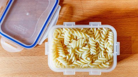 Ein Behälter mit gekochter Pasta steht auf einem Holzuntergrund, bereit zum Einfrieren für die spätere Verwendung.