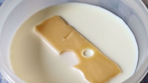 Wenn der Käse angetrocknet ist, einige Zeit in Milch einlegen, bis er wieder genießbar ist. Eine Käsescheibe liegt in einer Schüssel mit Milch, um sie vor dem Austrocknen zu bewahren und frisch zu halten.