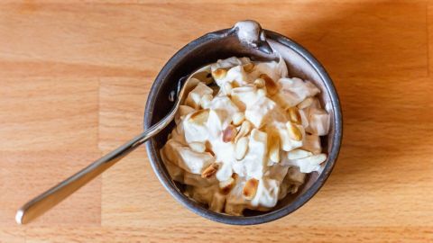 Eine Schüssel mit Käse-Salat steht auf einem Holzuntergrund, die Zutaten sind gemischt und bereit zum Servieren.