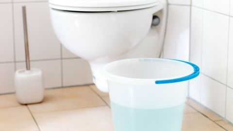 Badewasser kann man zum Abspülen der Toilette verwenden Ein Eimer mit Wasser steht neben einer Toilette in einem gefliesten Badezimmer. Das Bild zeigt eine einfache Alltagsszene.