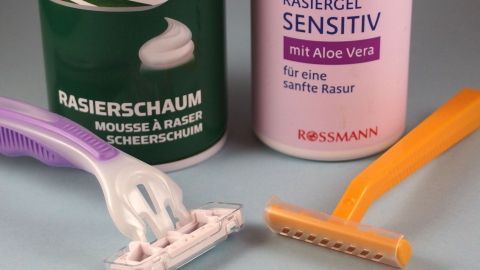 Ein Rasierer und ein Einwegrasierer liegen neben Rasiergel und -schaum im Badezimmer, bereit für eine gründliche Rasur.