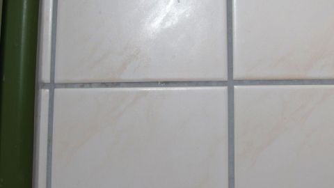 Auf einem engen Bereich von hellen Fliesen sind unschöne Kalkflecken sichtbar, die den Glanz beeinträchtigen.
