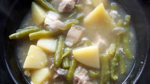 Ein herzhaftes Grüne-Bohnen-Eintopf mit Kartoffeln und Fleisch dampft in einer Schüssel, bereit zum Servieren.