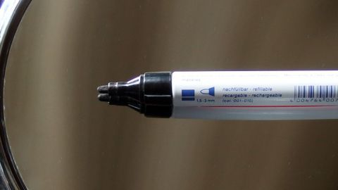 Edding ohne viel Druck mit Ajona Zahnpasta vom Spiegel entfernen. Ein Edding-Marker wird in einem Spiegel betrachtet, der glänzende Oberfläche reflektiert den Stift.