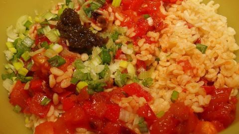 Bulgur und frisches Gemüse sind sorgfältig in einer Schüssel angerichtet, um einen bunten KISIR Salat zu kreieren.