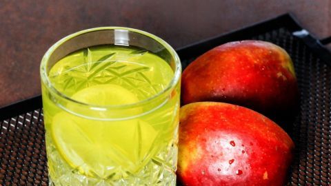 Ein Glas Apfel-Orangensaft steht auf einem Tablett neben frischen Äpfeln, in einem warmen, gemütlichen Ambiente.