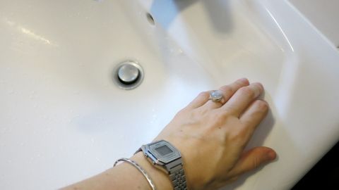 Eine Hand berührt die Oberfläche eines Keramikwaschbeckens, um mögliche metallische Kratzer zu überprüfen.