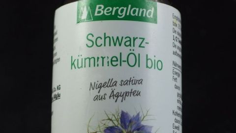 Schwarzkümmelöl, ein bewährtes Mittel im Nahen Osten, gegen Bronchitis und Asthma. Eine Flasche mit flüssigem Schwarzkümmelöl steht vor schwarzem Hintergrund und zeigt den Namen und die Inhaltsstoffe.