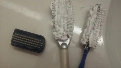 Haarbürsten und Kämme sind mit Rasierschaum gereinigt und liegen auf einem Waschbecken neben einem kleinen Kamm.