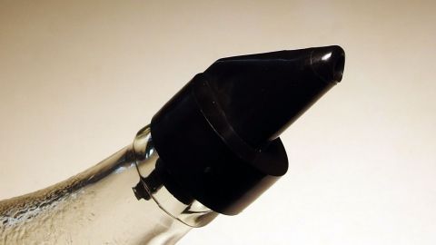 Eine Flasche mit einem speziellen Dosierverschluss steht in einem neutralen Umfeld, bereit, Pflanzenöl sparsam zu dosieren.