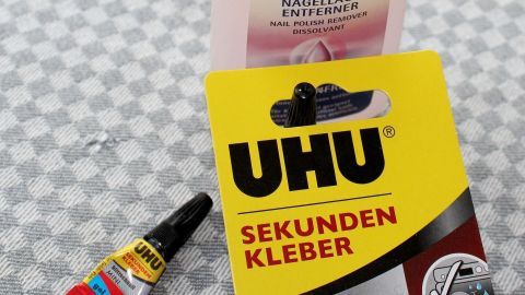 UHU Sekundenkleber-Tube und Nagellackentferner markiert mit "UVERISH" auf kariertem Untergrund; Kleber für schnelle Reparaturen.