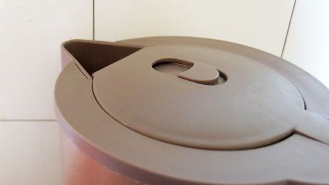 Fettflecken auf Kacheln ganz ohne Mühe entfernen, mit Dampf aus dem Wasserkocher und einem feuchten Lappen. Ein Kännchen steht auf der Küche mit Fliesen, bereit, Fettflecken zu entfernen. Der Deckel zeigt eine praktische Öffnung.