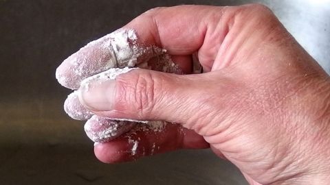 Eine Hand hält eine Mischung aus Mehl und Backpulver, während sie versucht, Sekundenkleber zu entfernen.