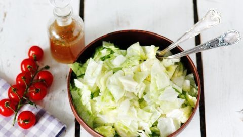 Ein rustikaler Salat in einer Schüssel wird mit würzigem Dressing begleitet und umgeben von frischen Kirschtomaten.