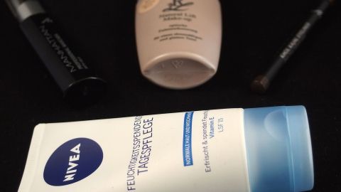 Mit Gesichtscreme bekommt man viele Make-Up- und ähnliche Flecken wieder vom Schminktisch. Auf einem Schminktisch liegen mehrere Make-Up Produkte, einschließlich einer Nivea-Creme. Sie sind ordentlich platziert.