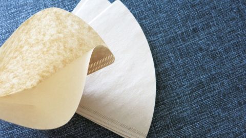 Ein Hamburger-Filter und eine servierte Schichtpapier liegen auf einem blauen Stoff, bereit zum Einsatz in der Küche.
