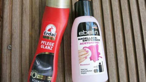 Pflegeprodukt für Schuhe und Nagellackentferner stehen auf einer Holzoberfläche nebeneinander, bereit zur Anwendung.