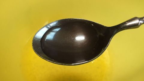 Die doppelte Menge an Eischnee erhält man wenn vor dem Schlagen einen Esslöffel kaltes Wasser dazugibt. Ein Löffel steht auf einer gelben Oberfläche, während Eischnee in der Nähe geschlagen wird, um die Menge zu verdoppeln.