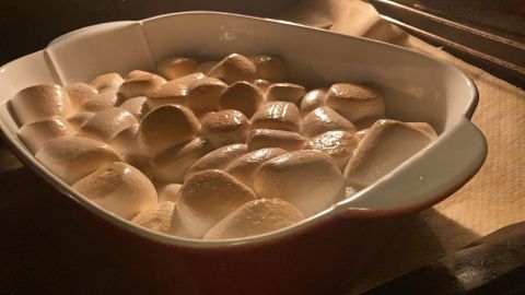 Der Auflauf aus Marshmallows bräunt sanft in einer Backform im Ofen, umgeben von warmem Licht und köstlichem Duft.