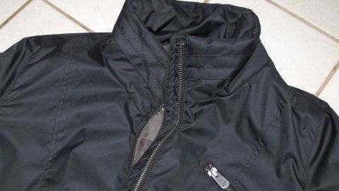 Eingetrocknete Harzflecken auf dem Anorak doch noch entfernt: mit einem Sodabad. Ein schwarzer Anorak liegt auf einem hellen Bodenfliesen, bereit, im Sodabad gewaschen zu werden, um Harzflecken zu entfernen.