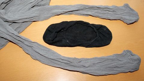 Strumpfhosen liegen auf einem Tisch, umgeben von einem schwarzen Füßling, der zusätzliche Halt bietet.