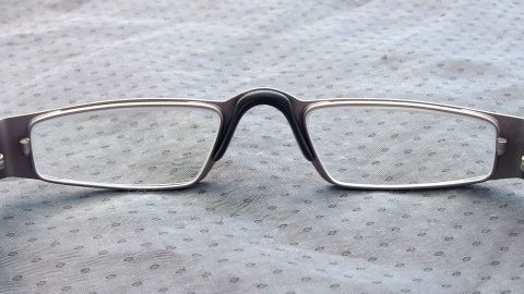 Eine Brille liegt auf einem blauen Tuch, die Gläser glänzen klar und sauber, bereit für den Gebrauch.