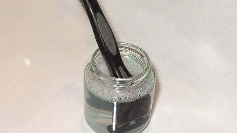 Rasierklingen bleiben länger scharf mit Spülmittel. Ein schwarzer Rasierpinsel steht in einem Glas mit Flüssigkeit, um die Rasierklingen länger scharf zu halten.